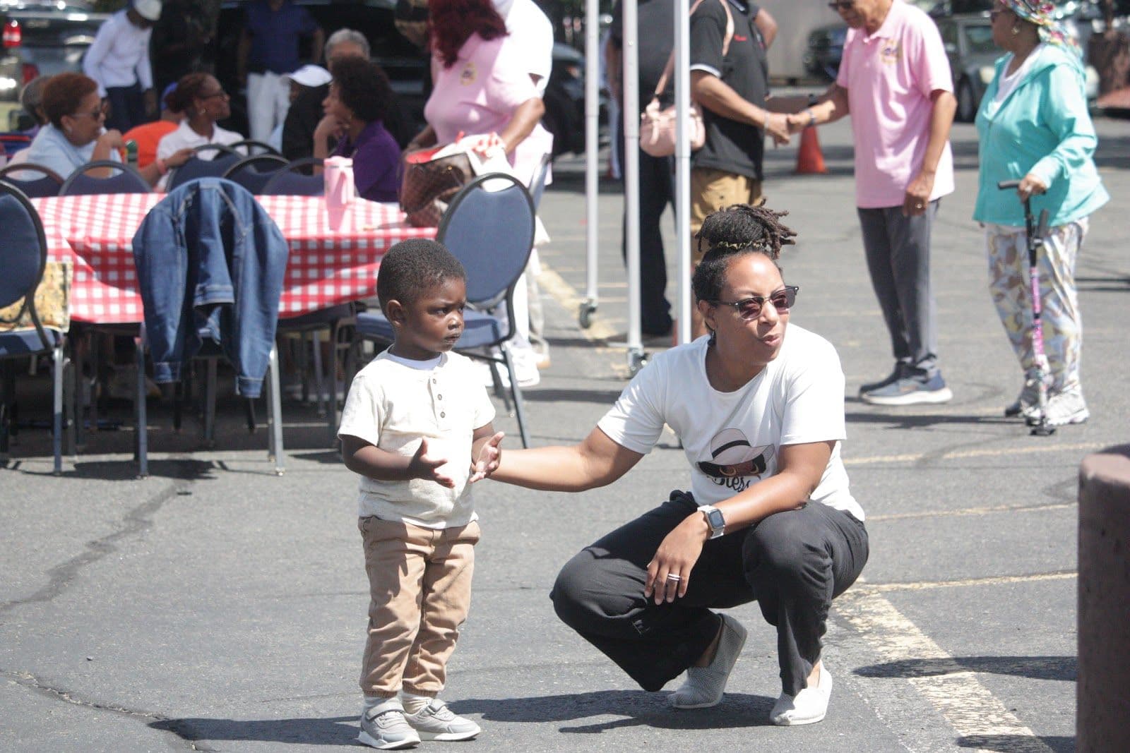 A member kneeling to greet a small child at a church event.
