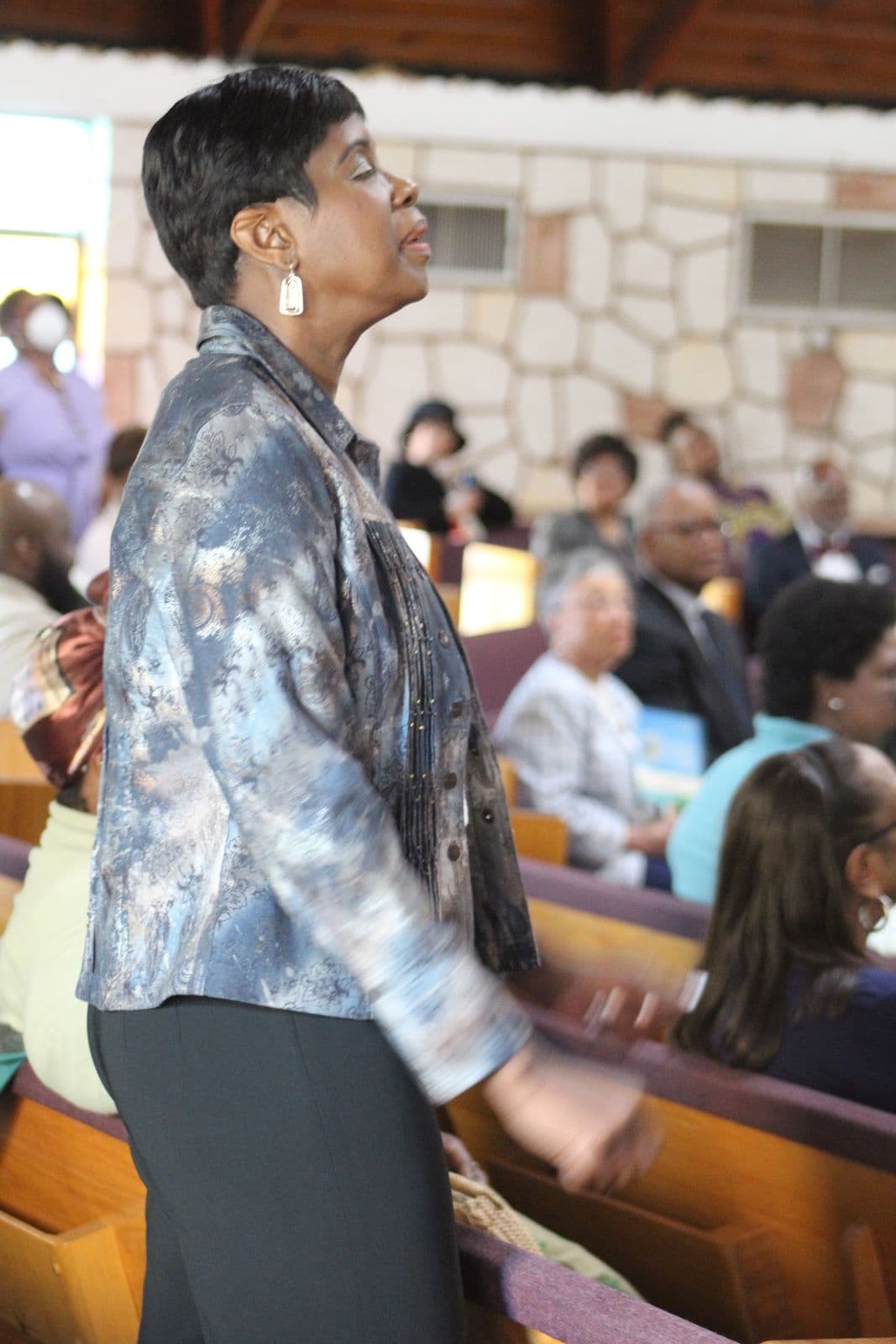 A member standing in worship with her eyes lifted