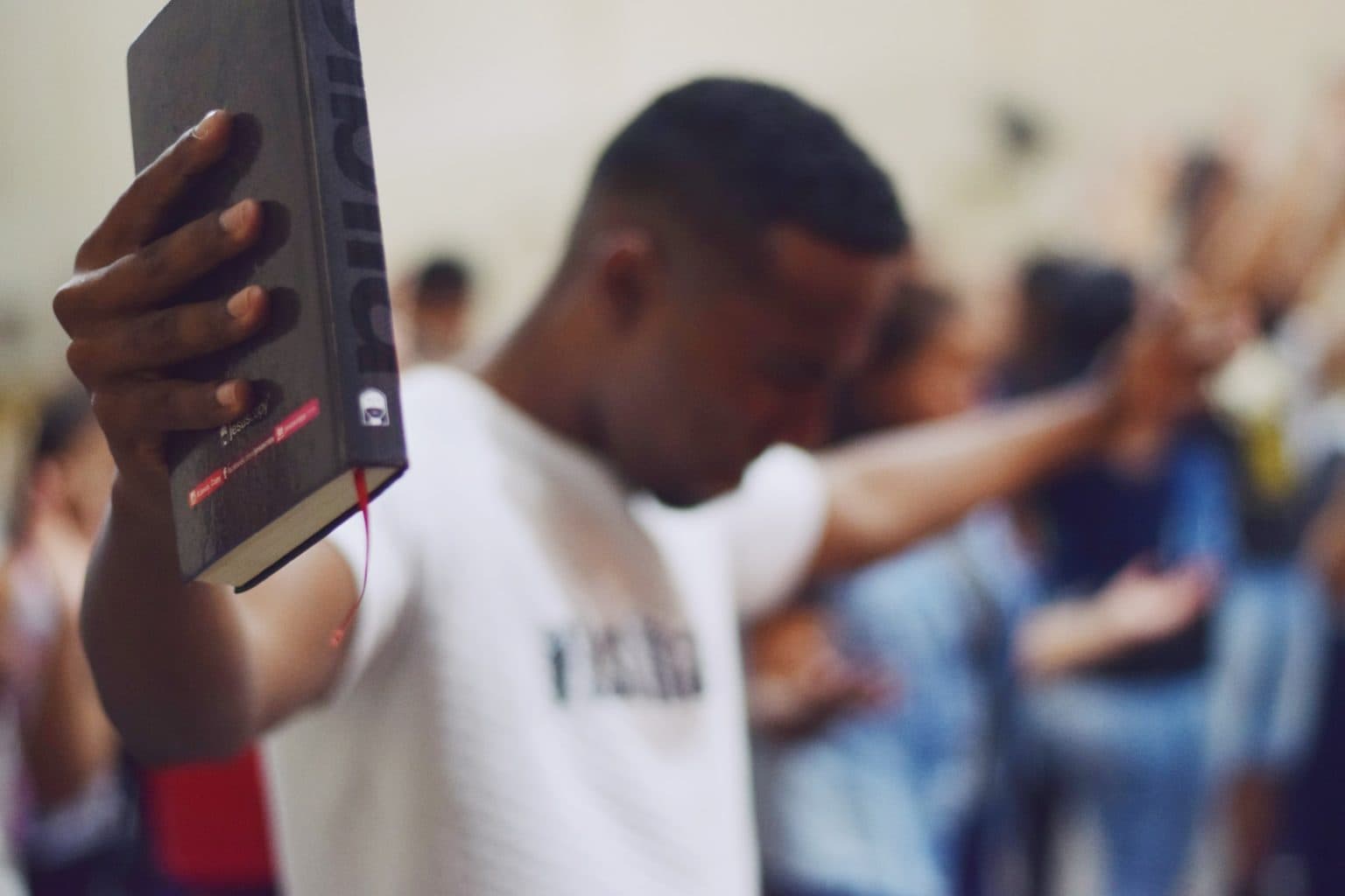 A young man holding a Bible high in worship